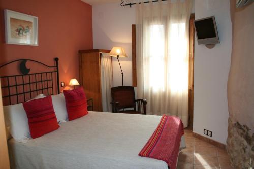 a bedroom with a large bed with red pillows at La Alquería in Ráfales