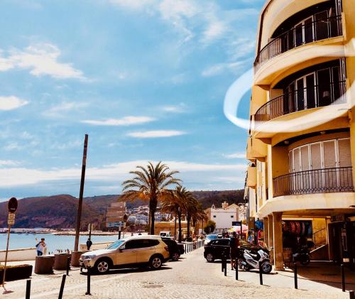 uma rua com carros estacionados ao lado de um edifício em Vista Azul em Sesimbra