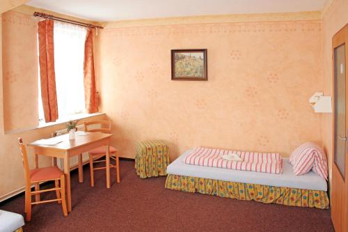 a bedroom with a bed and a table and a desk at Penzion U Michala in Prášily