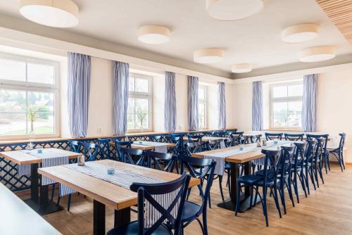 a dining room with tables and chairs and windows at Penzion U Michala in Prášily