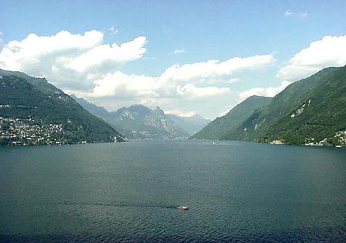a large body of water with mountains in the background at Hotel Dischma - FREE BUS AND TRAIN TICKET in Lugano