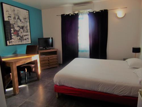a bedroom with a bed and a desk and a television at Hôtel Domaine le Milos in Castries