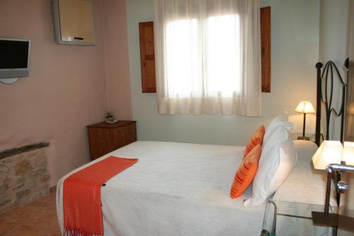 a bedroom with a bed with orange pillows and a window at La Alquería in Ráfales