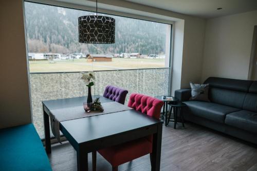 a living room with a table and a couch and a large window at Apart Julia in Längenfeld