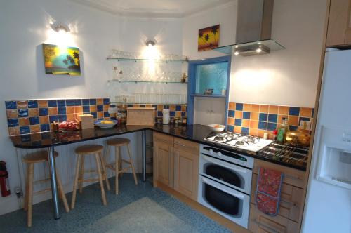 a kitchen with a stove and a counter with stools at Seawall, 30A Burlington Road in Swanage