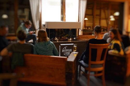 een groep mensen die rond een bar zitten met een fles bier bij Mountain Lodge Sedrun in Sedrun