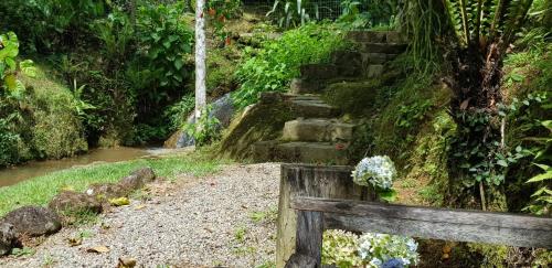 un banc en bois assis devant un escalier en pierre dans l'établissement Pousada Vertente das Águas, à Lumiar