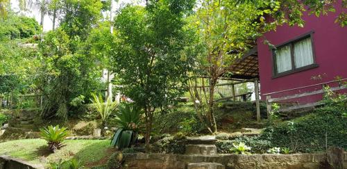 a pink house with a garden in front of it at Pousada Vertente das Águas in Lumiar