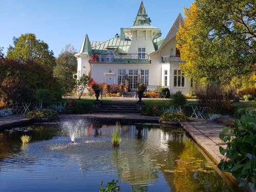 una gran casa blanca con un estanque y una fuente en Villa Gransholm, en Gemla