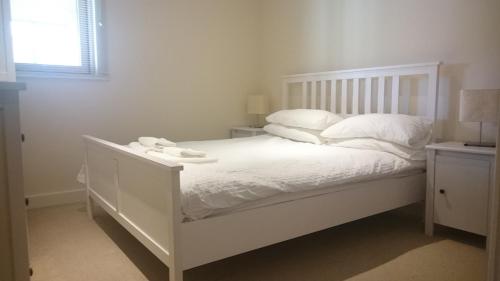 een wit bed met witte lakens en kussens erop bij Harbourside Apartment in Whitehaven