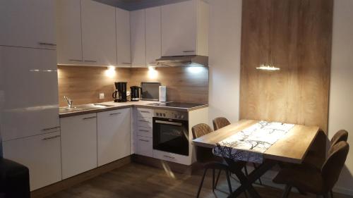 una cocina con armarios blancos y una mesa con sillas. en Emsgold en Oberlangen