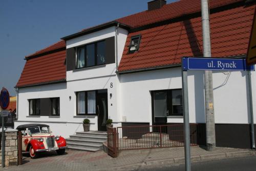 an old red car parked in front of a house at Villa Rynek in Góra Świętej Anny