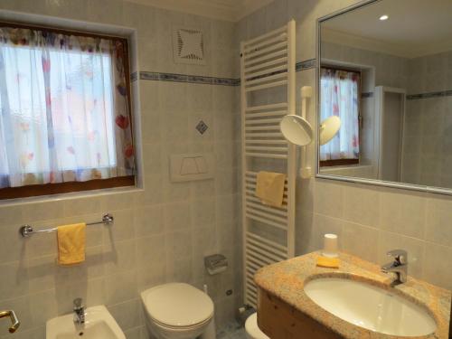 a bathroom with a sink and a toilet and a mirror at Hotel Ciasa Ai Pini in San Cassiano