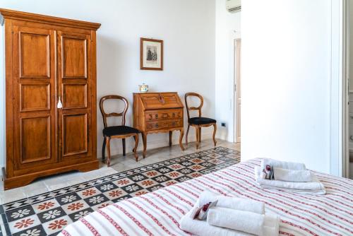 シラクーサにあるAppartamento Calarossaのベッドルーム1室(ベッド1台、ドレッサー、椅子付)