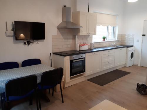 a kitchen with white cabinets and a table and a sink at Delphi Cottage in Ashbourne