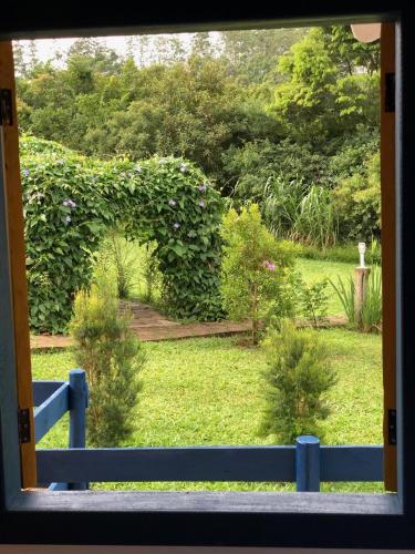 a view of a garden through a window at João e Maria Restaurante e Chalés in Tiradentes