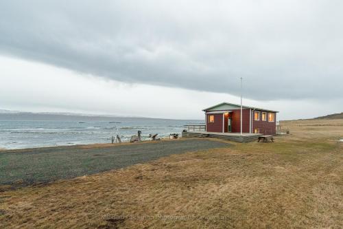 a small house on a beach near the ocean at Borgir - The House by the Sea in Borgir