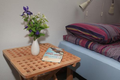 a table with a vase of flowers and a book at Bed & Breakfast Horsens in Horsens