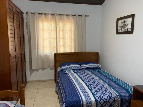 une chambre avec un lit avec des draps bleus et une fenêtre dans l'établissement Búzios Praia Rasa Casa 4, à Búzios