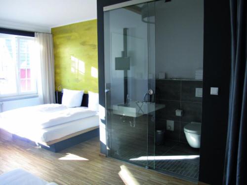 a bedroom with a bed and a glass shower at OX Hotel in Heitersheim