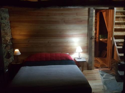 a bedroom with a bed and a wooden wall at Casa da Carvalha in Lousã