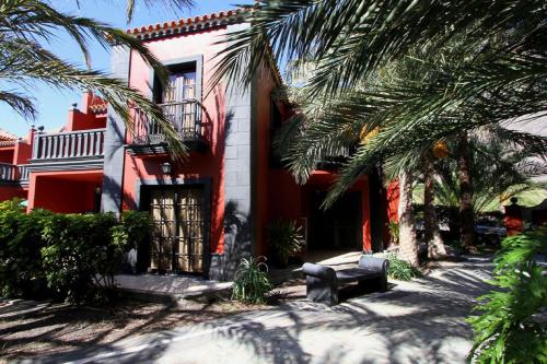 a red house with palm trees in front of it at Apartamentos Punta Marina in Valle Gran Rey