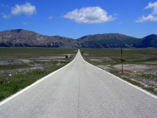 an empty road in the middle of a field at Il Piccolo Tibet - Gran Sasso in LʼAquila