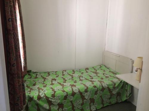 a small bedroom with a bed with a green comforter at Appartement L Eiffel in Coulonges