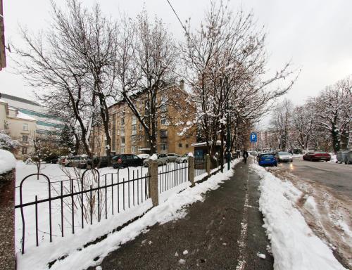 a fence is covered in snow next to a street at Apartman Vills in Sarajevo