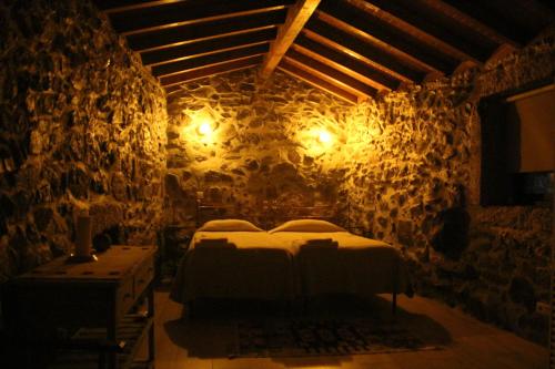 セロリコ・デ・バストにあるQuinta da Chouza Agroturismo e Enoturismoの石壁のベッドルーム1室(ベッド2台付)