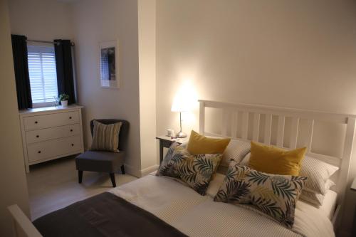 een slaapkamer met een bed met kussens en een stoel bij East Bridge Apartments in Enniskillen