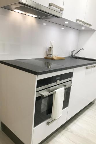 a white kitchen with a black counter top at B&B Kelly Plus in Lausanne