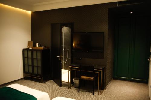 a bedroom with a bathroom with a shower and a television at Hotel Rubis in Ferizaj