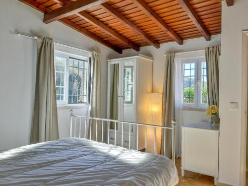 a bedroom with a bed and two windows at The Beachfront Casa da Rampa in Sintra