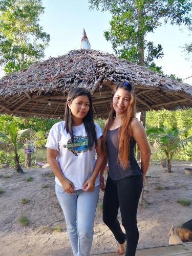 two girls are standing in front of a hut at Villa Encantador Resort in San Vicente