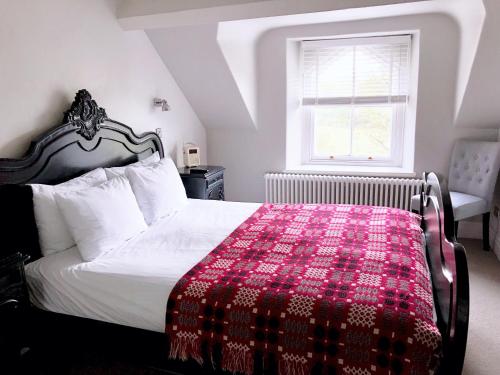 a bedroom with a bed with a red blanket on it at Olif in Betws-y-coed