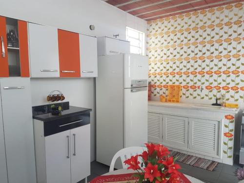 una cocina con armarios blancos y una mesa con flores rojas en Casa em Cabo Frio, Espaçosa e Confortável, en Cabo Frío