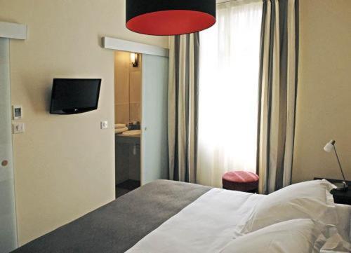 Schlafzimmer mit einem Bett mit roter Lampe und einem TV in der Unterkunft Hôtel Ronsard in Tours