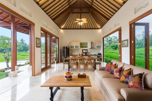 an open living room with a couch and a table at Champaca Luxury Villas Ubud in Ubud