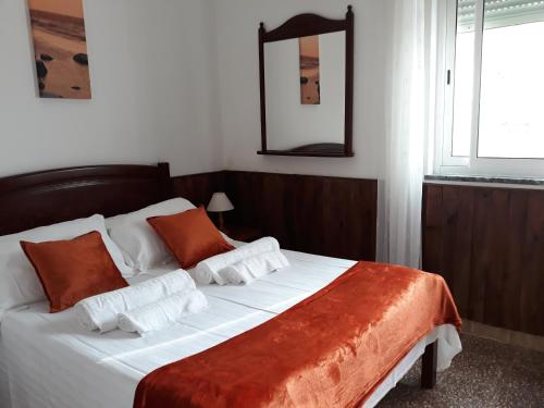 a bedroom with a large bed with orange and white pillows at Casa Dorita in Odeceixe