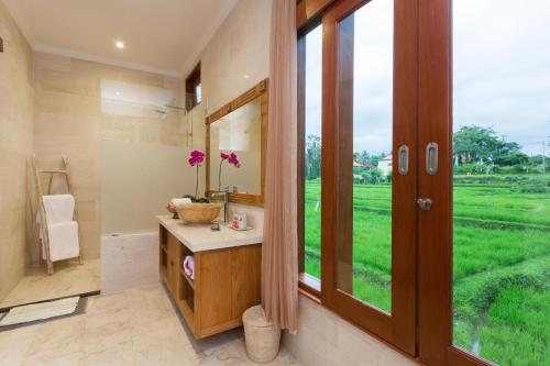 a bathroom with a sink and a window with a view at Champaca Luxury Villas Ubud in Ubud