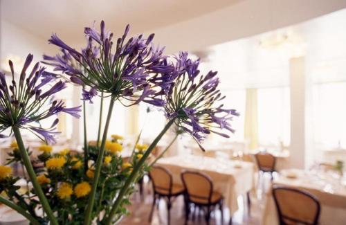 a vase filled with purple flowers on a table at Hotel Torremaura in Milano Marittima