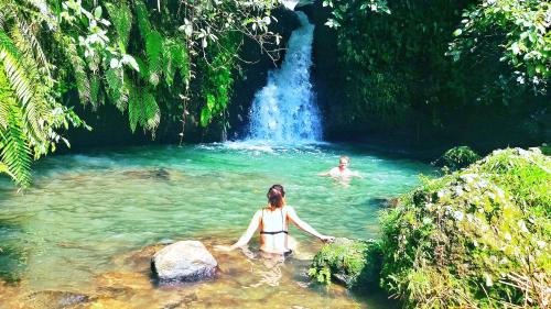 a woman in a pool of water in front of a waterfall at Ariel Bungalow Tetebatu in Tetebatu