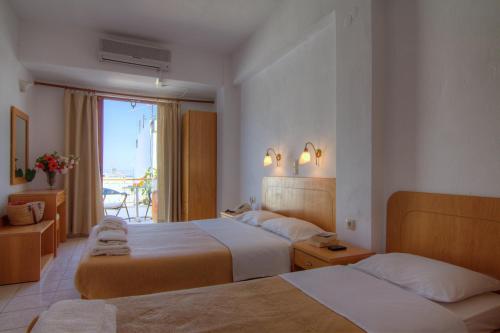 a hotel room with two beds and a window at Adonis Hotel in Agia Galini