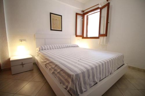 a white bedroom with a bed and a window at Cabañas 59 in Denia