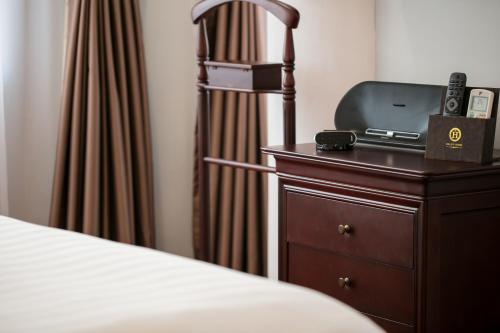 a bedroom with a bed and a dresser with a television at Halais Hotel in Hanoi