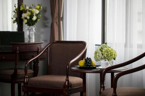 a table with a bowl of fruit and flowers on a chair at Halais Hotel in Hanoi
