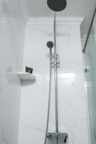 a shower in a bathroom with white walls at Halais Hotel in Hanoi