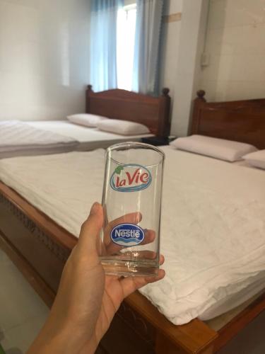 a person holding a glass in front of a bed at Thien Thanh Hotel in Vĩnh Long