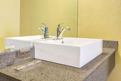 a bathroom sink with two faucets on a counter at Days Inn by Wyndham St. Petersburg Central in St Petersburg